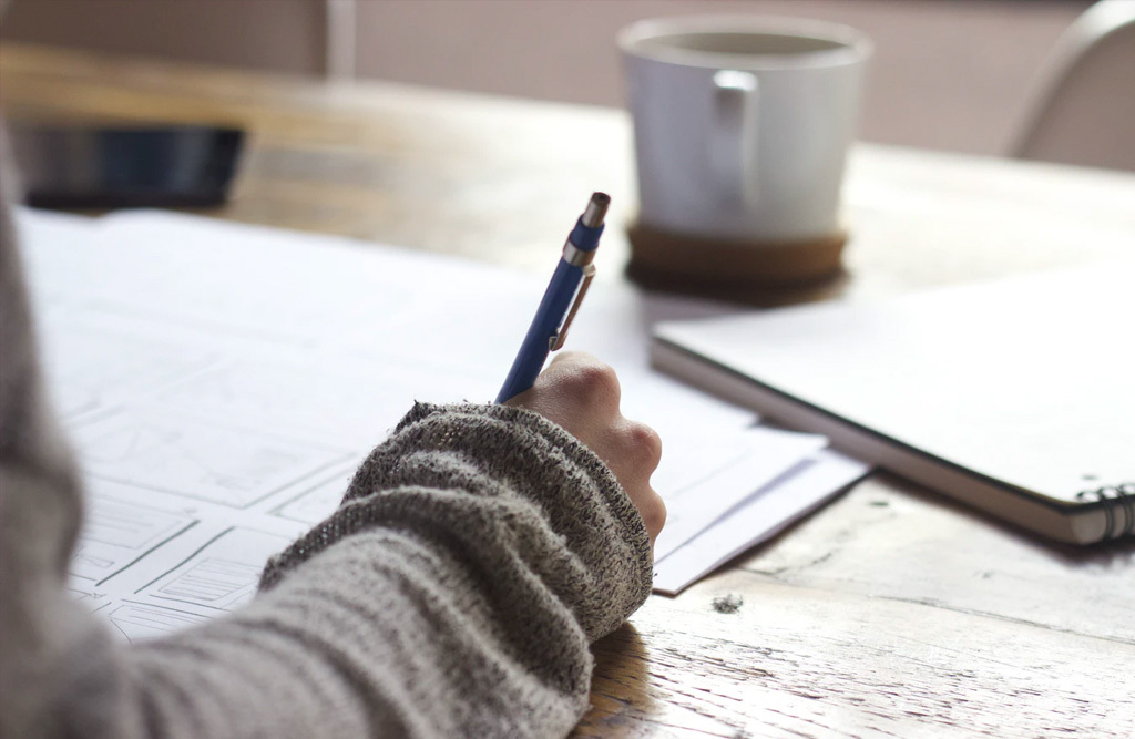 Hand holding pen writing on paper