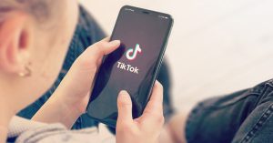 person holding phone with 'tiktok' logo on screen