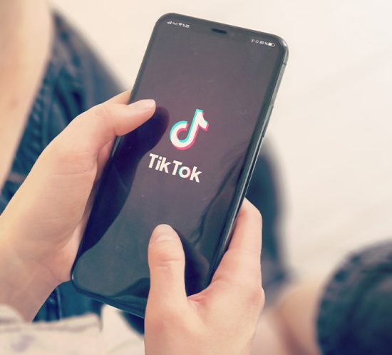 person holding phone with 'tiktok' logo on screen